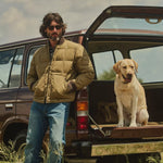 Filson Heritage Cotton Down Jacket in Light Brown worn zipped over a plaid flannel shirt and jeans, showing the relaxed fit 